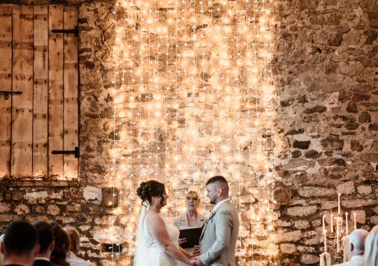 Romantic wedding at Eden Barn, Cumbria – rustic stone barn with fairy lights and countryside views. Bride and groom at Eden Barn, a charming wedding venue in Cumbria with exposed stone walls and wooden beams. Rustic wedding reception at Eden Barn – elegant tablescapes, candlelight, and floral decor in a historic barn setting. Outdoor wedding ceremony at Eden Barn, Cumbria – scenic countryside backdrop with a beautifully styled aisle. Bride and groom sharing their first dance under fairy lights in the atmospheric Eden Barn, Cumbria. Candid wedding photography at Eden Barn – newlyweds enjoying a golden hour moment in the Cumbrian countryside. Intimate wedding dinner at Eden Barn, Cumbria – rustic wooden tables, greenery, and soft lighting. Eden Barn wedding venue – a romantic, family-run barn in the heart of Cumbria’s rolling countryside. Bridal portrait at Eden Barn, Cumbria – stunning wedding dress captured in soft natural light. Groom’s first look reaction at Eden Barn – emotional moment in a rustic barn wedding setting. Evening wedding reception at Eden Barn – cozy, candlelit barn with fairy lights and dancing. Wedding cake display at Eden Barn, Cumbria – beautifully decorated rustic cake with floral accents. Bridal party celebrations at Eden Barn – bridesmaids and groomsmen enjoying the stunning countryside venue. Sunset wedding photography at Eden Barn – breathtaking golden hour shots of the newlyweds. Confetti moment at Eden Barn, Cumbria – joyful wedding guests celebrating outside the historic stone barn. Rustic wedding details at Eden Barn – boho-inspired table settings, wildflowers, and vintage decor. Emotional wedding vows at Eden Barn – heartfelt ceremony in a charming countryside barn setting. Bride and groom walking hand in hand at Eden Barn – natural and relaxed wedding photography. Live wedding band at Eden Barn – guests dancing under the twinkling fairy lights in a rustic barn venue. Luxury barn wedding at Eden Barn, Cumbria – elegant styling meets countryside charm for the perfect day.